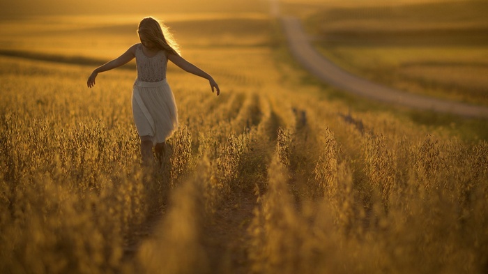 Girl in white dress running through a golden field in Nebraska