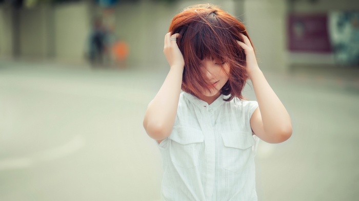 Asian woman with short red hair touching her head