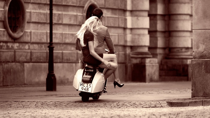 Couple riding a moped on a cobblestone street