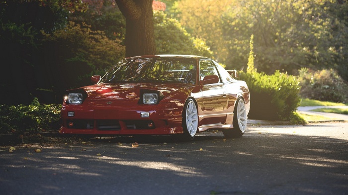 Red Nissan 240SX parked on a tree-lined street