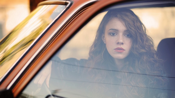 Young woman with red hair in a car