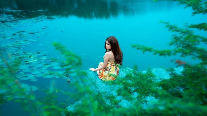 Woman sitting on a rock by a lake