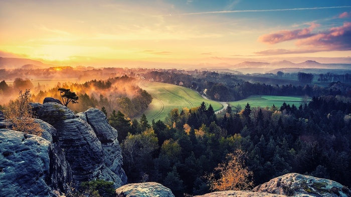 Misty mountain landscape at sunrise with rocky foreground
