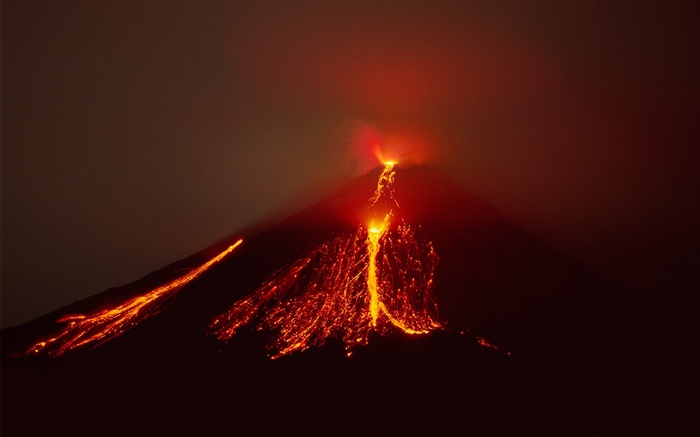 Volcano erupting with lava flows at night