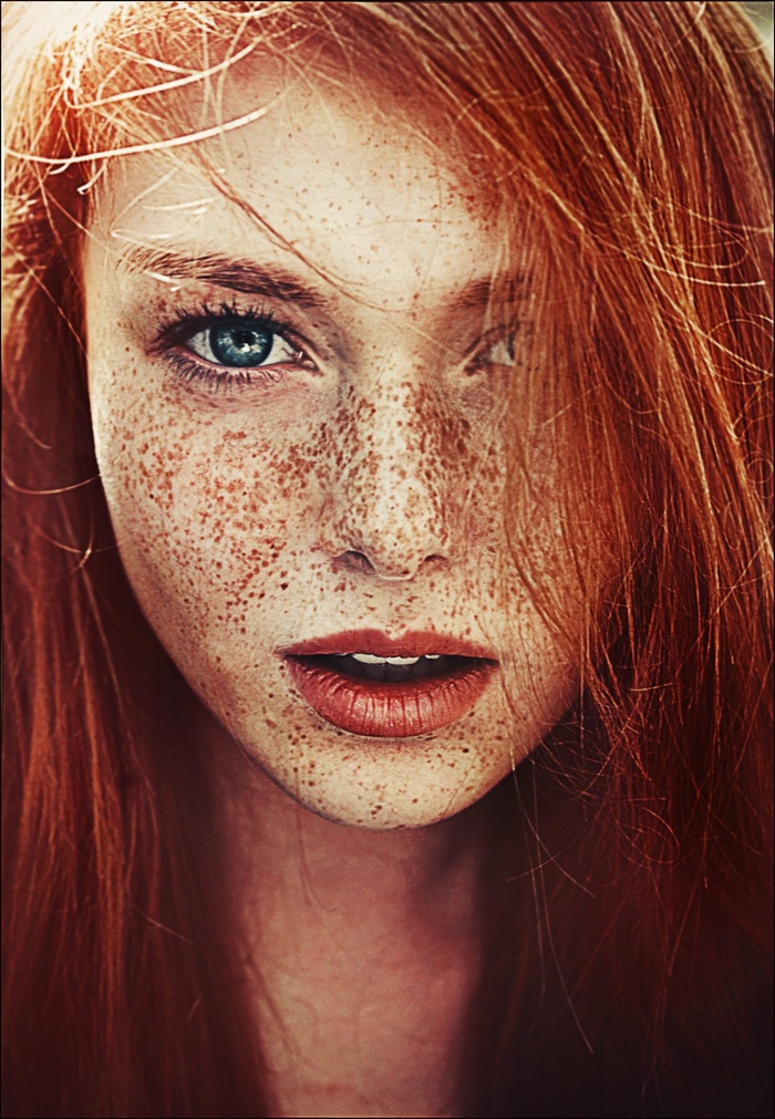 Close-up portrait of a freckled redhead woman with blue eyes