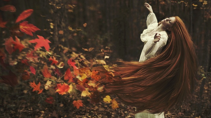 Redhead woman dancing with autumn leaves
