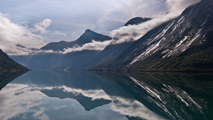 Mountains reflected in a calm lake under a cloudy sky