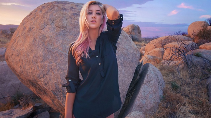 Woman with pink-streaked blonde hair posing outdoors