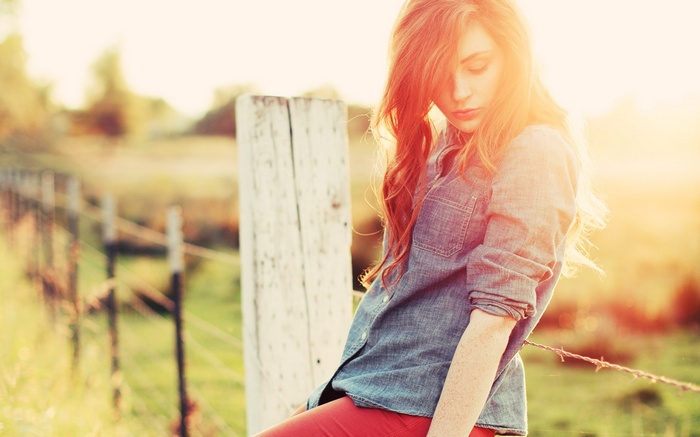 Woman with freckles and red hair by a fence