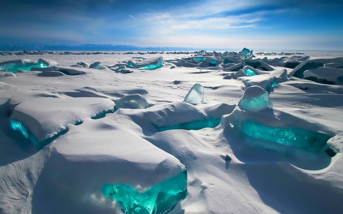 Frozen landscape with glowing blue ice formations under a bright sky