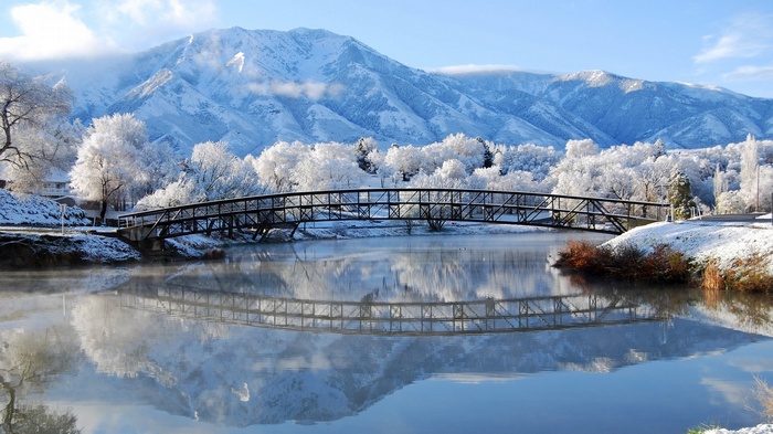Snow-covered mountains and bridge over a river in winter