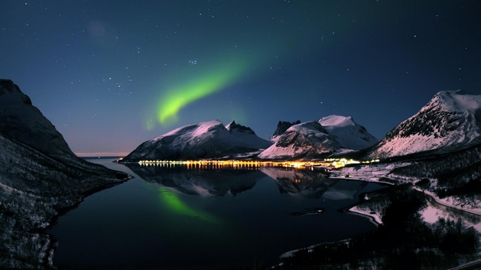 Aurora Borealis over snow-covered mountains and a bay