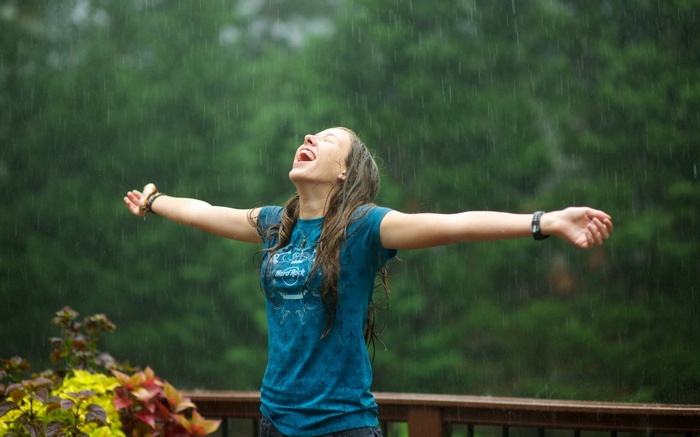Woman enjoying the rain with arms outstretched
