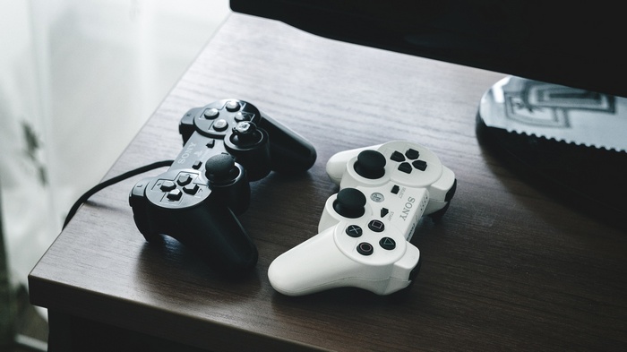 Two Sony PlayStation 3 controllers on a wooden table