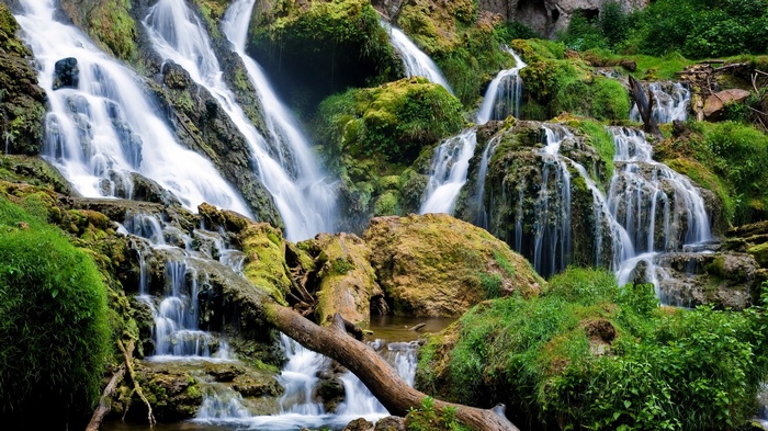 A cascading waterfall flows over moss-covered rocks