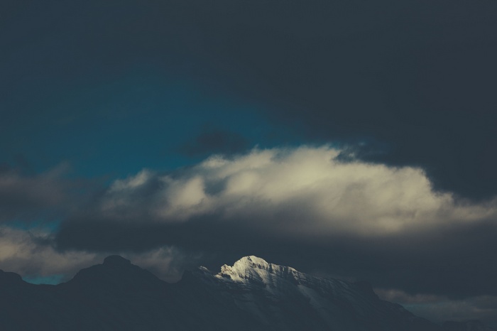 Snow-capped mountains under dark clouds