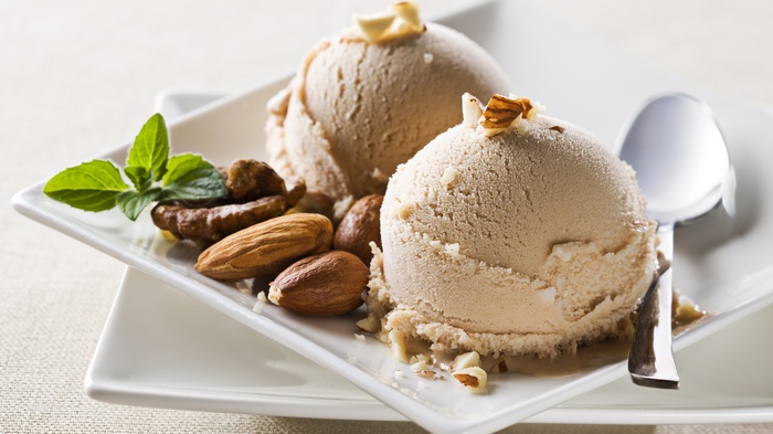 Two scoops of ice cream with nuts and mint on a plate