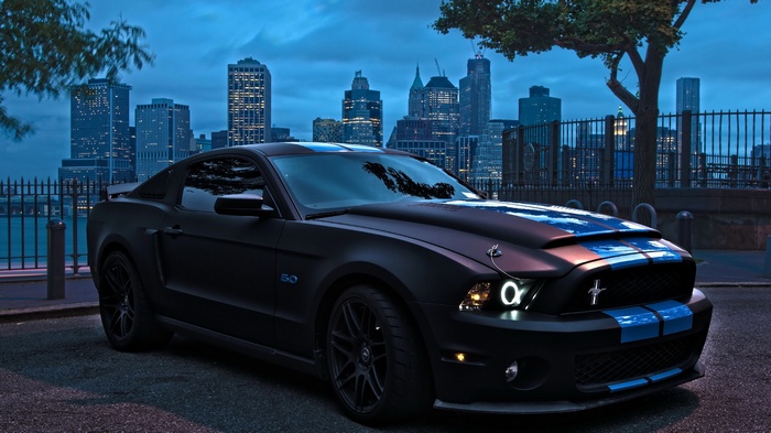 Matte black Ford Mustang with blue stripes in city