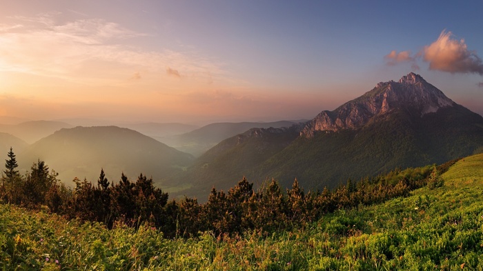 Misty mountains at sunset with green foreground