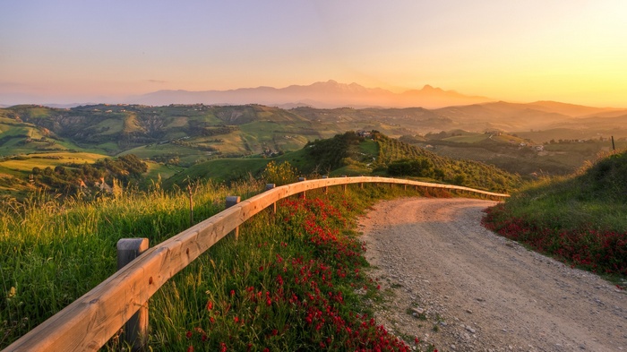 A winding dirt road through rolling hills at sunset