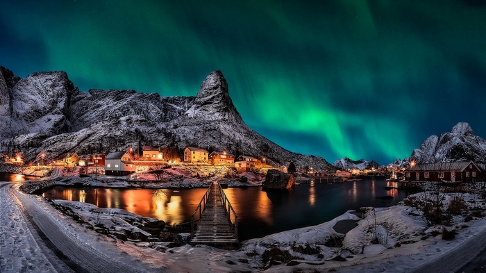 Aurora Borealis over a Norwegian village with snowy mountains
