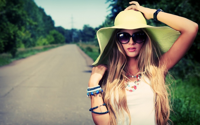 Woman with hat and sunglasses on a road