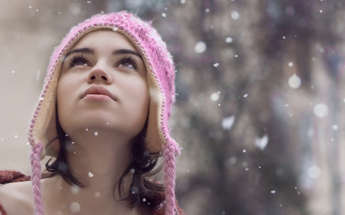 Woman in pink hat looking up at snow