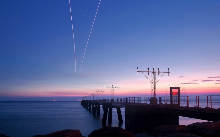Airport runway lights over the ocean at sunset
