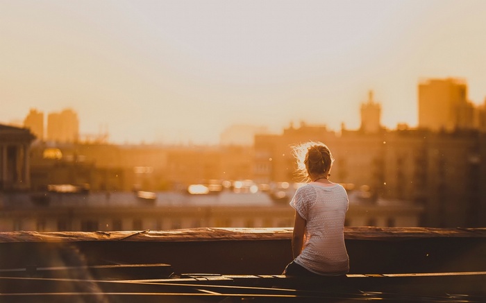 Woman sitting on a rooftop at sunset