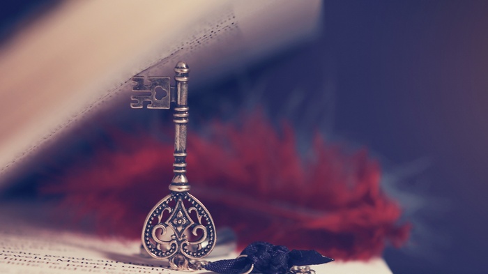 Antique key on an open book with red feather