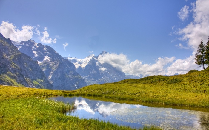 Mountains reflected in a calm lake with green hills