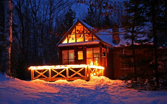 Cozy cabin in a snowy forest at night with lights