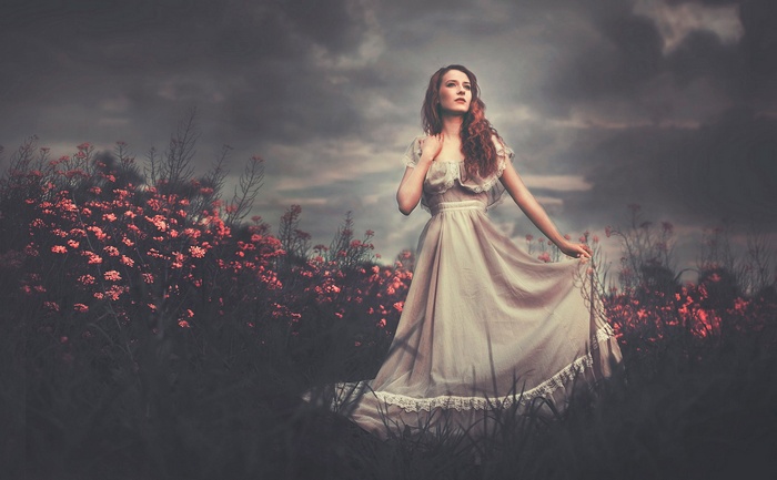 Redhead woman in a dress in a field of flowers