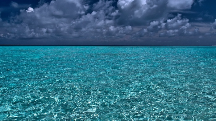 Turquoise ocean water under dark clouds
