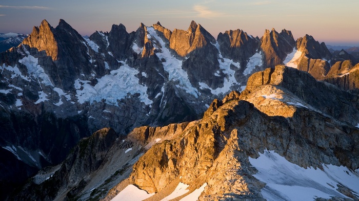Jagged mountain peaks with snow and glaciers at sunrise