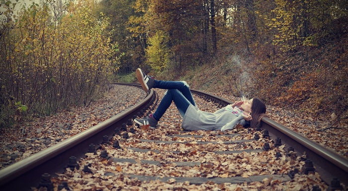 Woman lying on railway tracks smoking