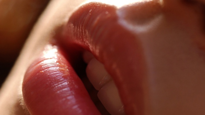 Close-up of a woman's glossy red lips and teeth
