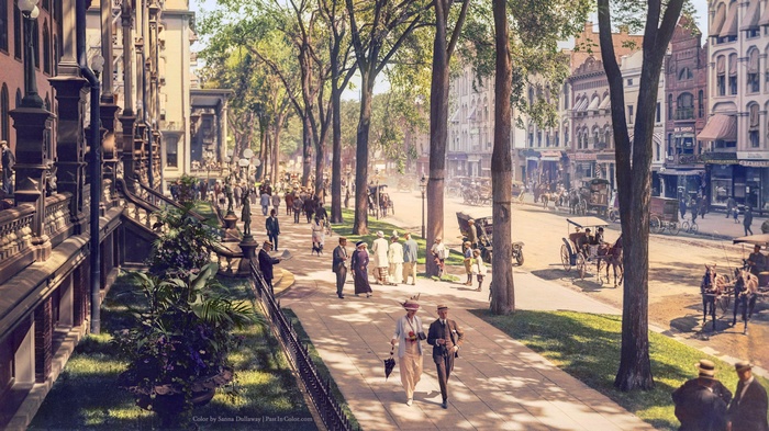 Colorized vintage street scene with pedestrians and horse-drawn carriages