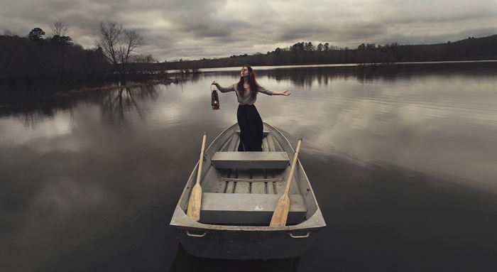 Woman holding a lantern in a rowboat on a lake