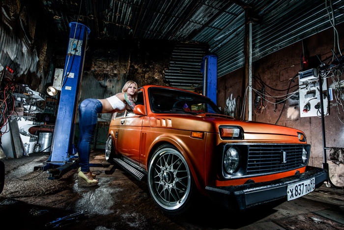 Woman posing with a Lada Niva car in a garage