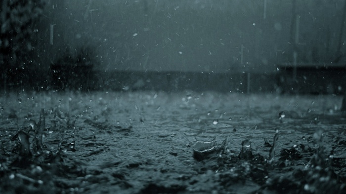 Rain falling on a dark, wet surface