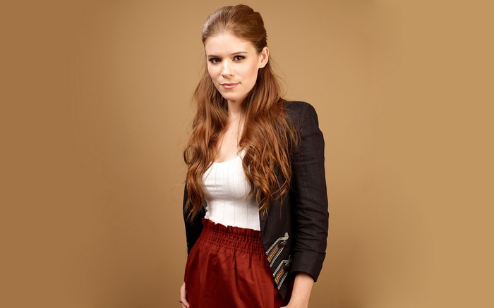 Kate Mara in a black jacket and red skirt