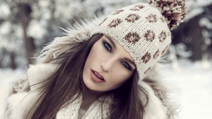 Woman in winter hat and fur coat in snow