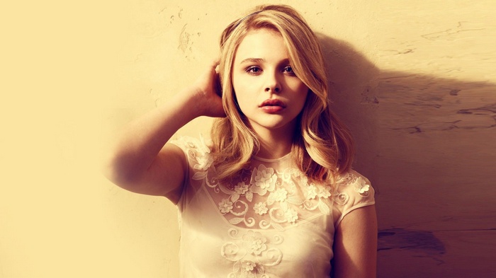 Chloë Grace Moretz posing against a textured wall