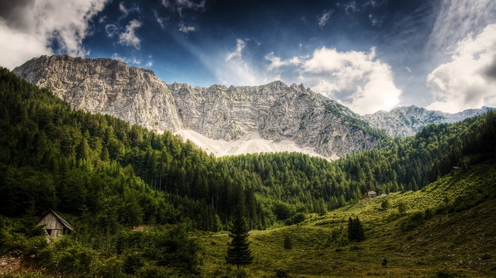 Wooden cabin in a mountain forest with dramatic clouds