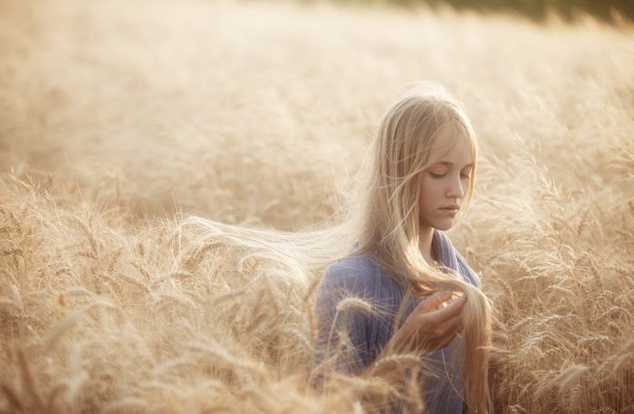 Young woman with blonde hair in a wheat field