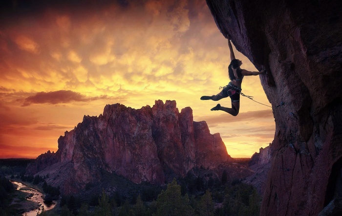 Woman rock climbing at sunset with mountains