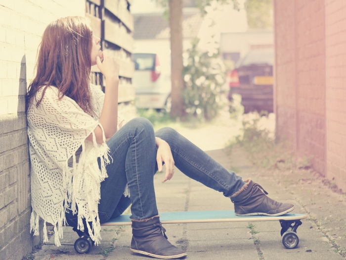 Woman sitting on a skateboard outdoors