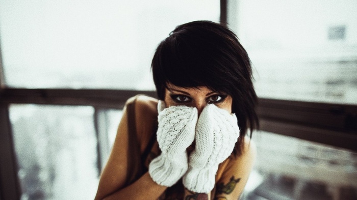 Brunette woman with tattoos wearing white gloves