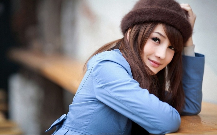 Asian woman with long brown hair wearing a hat and trench coat